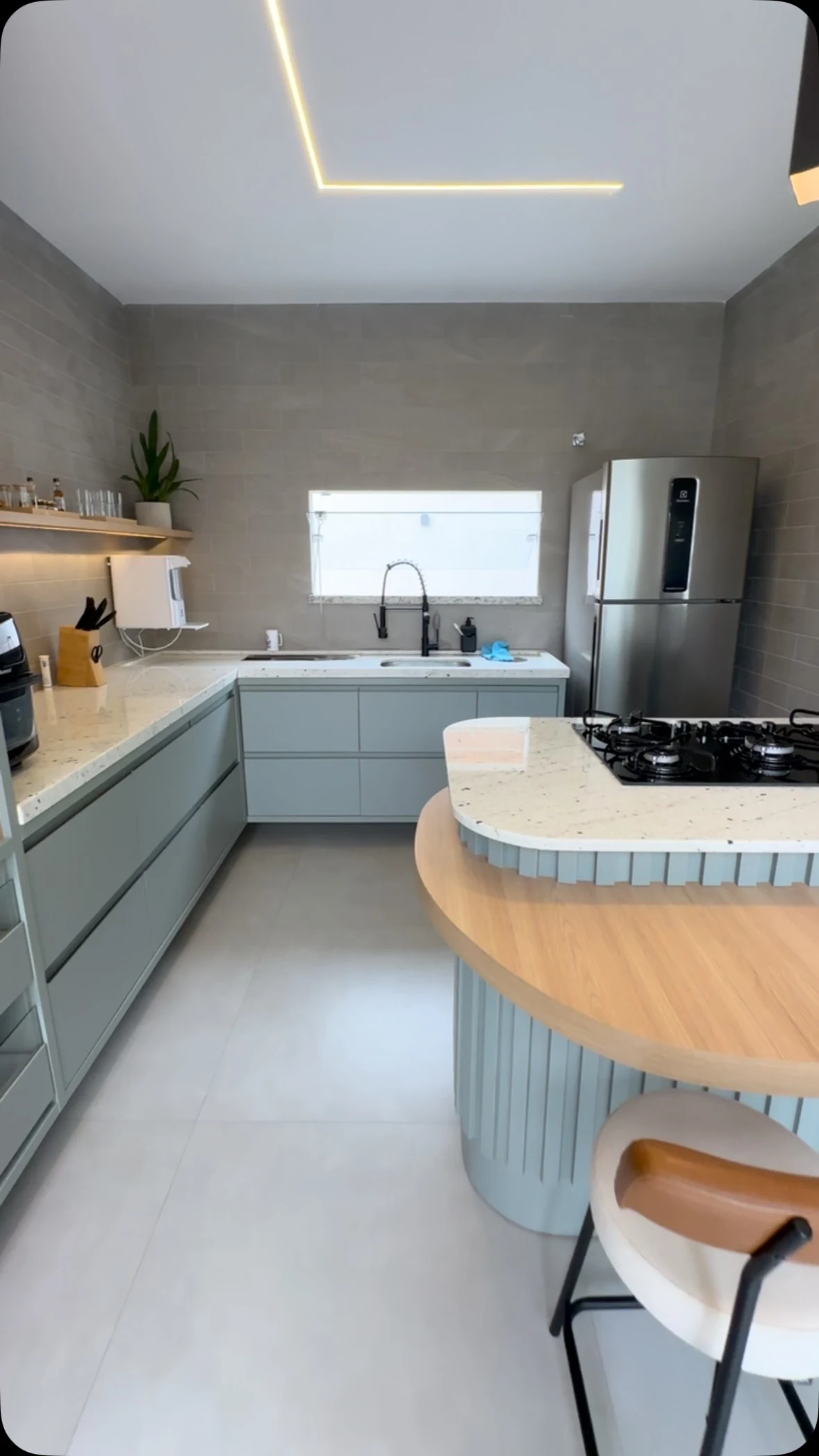 Cozinha planejada com armários verdes e ilha curva com bancada de madeira