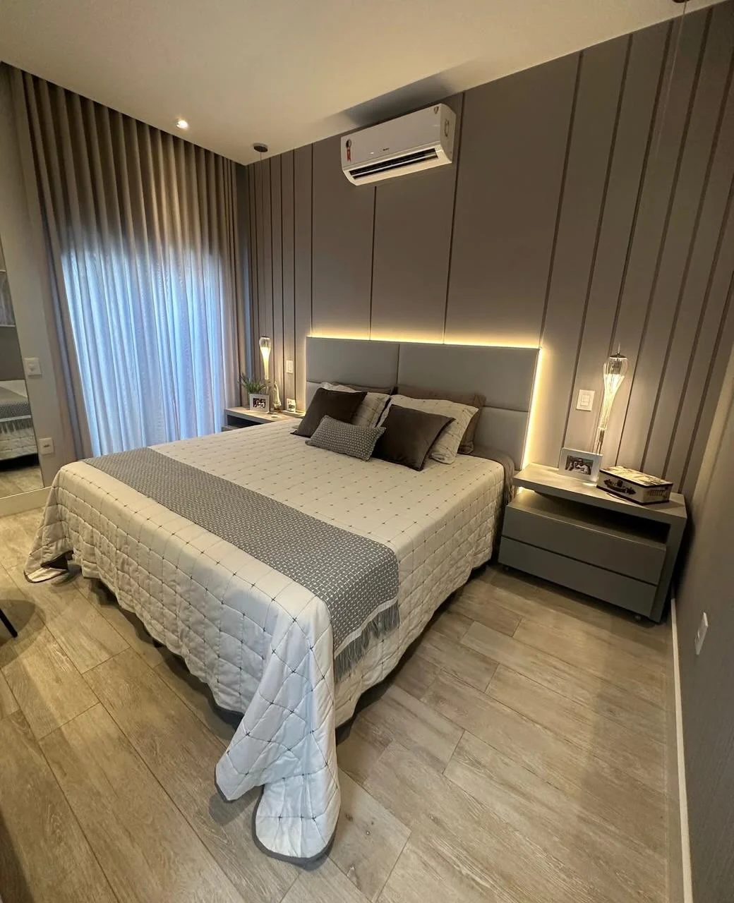 Quarto de casal com painel estofado, criados-mudos suspensos e iluminação embutida